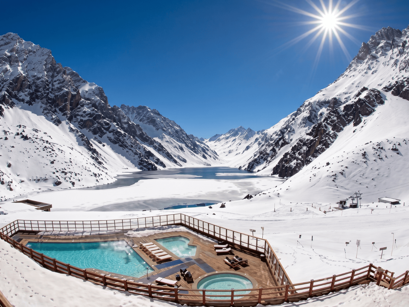 Piscina aquecida do Hotel Portillo cercada por neve, com vista para a Laguna del Inca e a Cordilheira dos Andes no Chile.